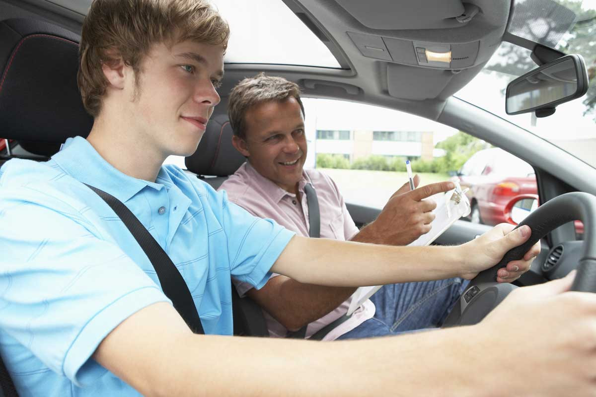 Driving instructor at Get Drivers Ed demonstrating proper driving techniques to a student in a driving simulator.