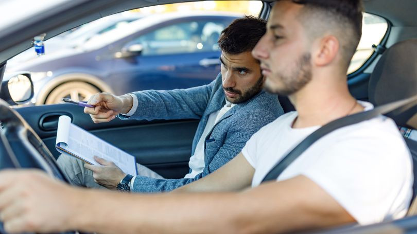 A teenage boy driving a car with a worried expression, symbolizing the higher insurance rates young male drivers face.