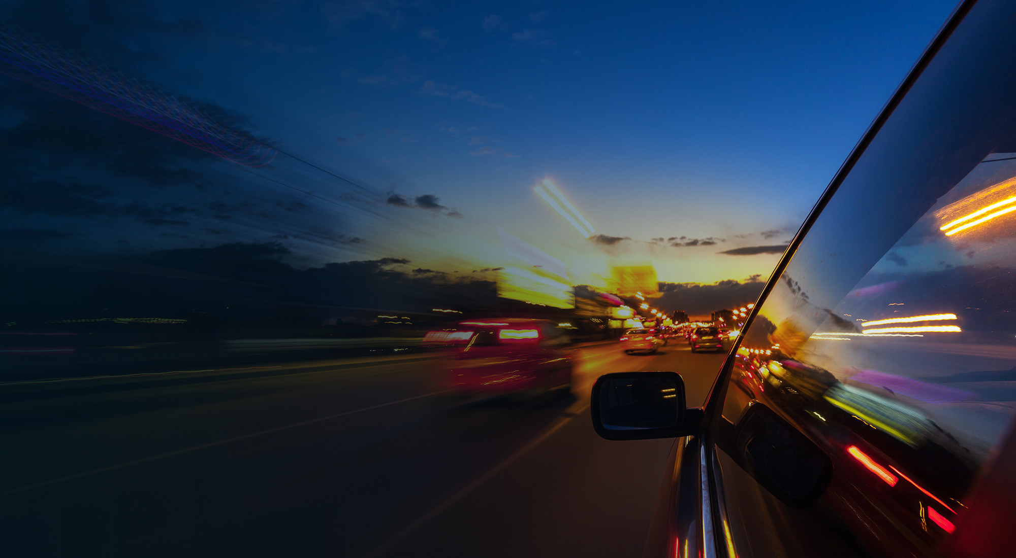 A car driving on a dark road with headlights on after Daylight Saving Time ends.