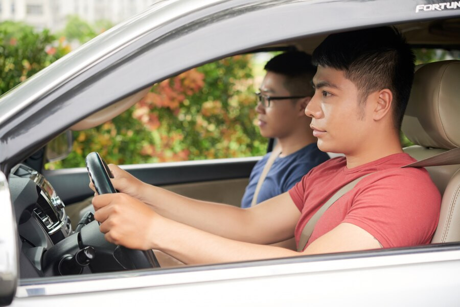 Adult driving instructor guiding student through driving techniques