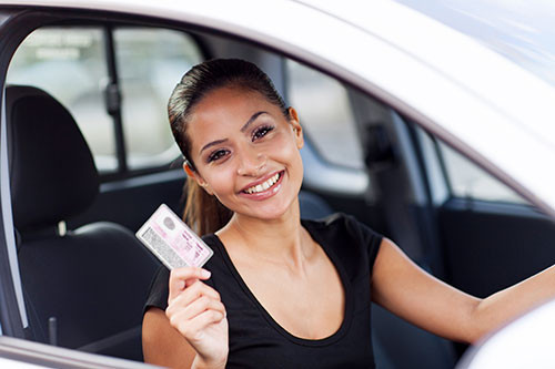 Young adult receiving their driver’s license at the DMV after turning 18, showcasing the benefits of waiting to get licensed.