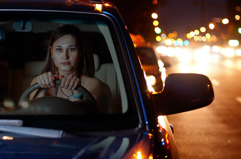 A driver navigating a dark road at night, with headlights illuminating the path and tips for night driving displayed on the screen.