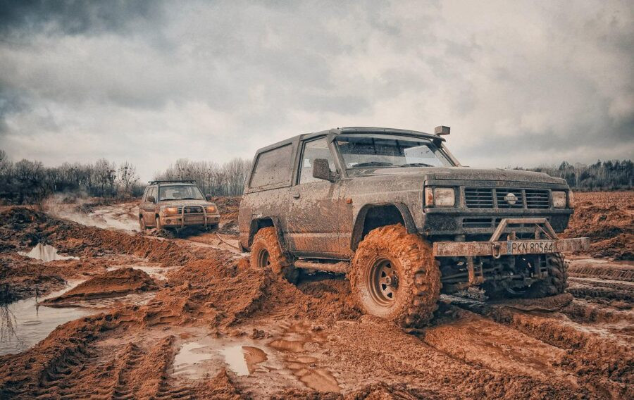 Car wheels stuck in mud with a driver using tools to create traction.