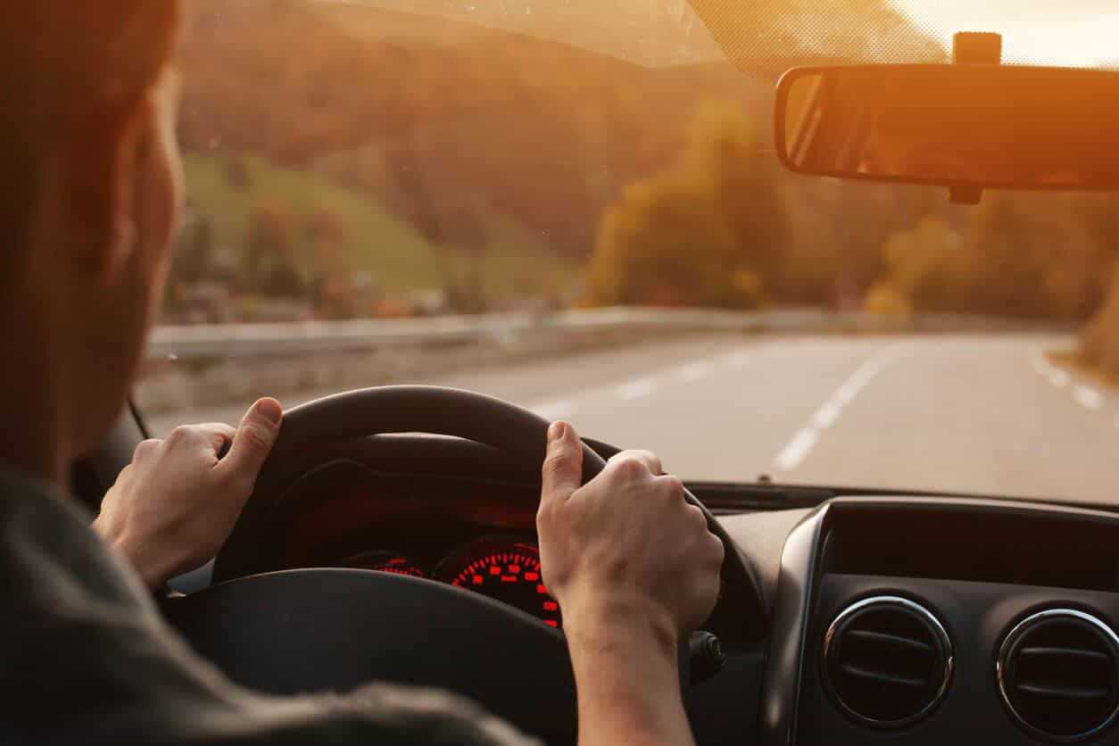 Driver holding a steering wheel with Get Drivers Ed guide on the dashboard, symbolizing mastering the driving licensing and points system.