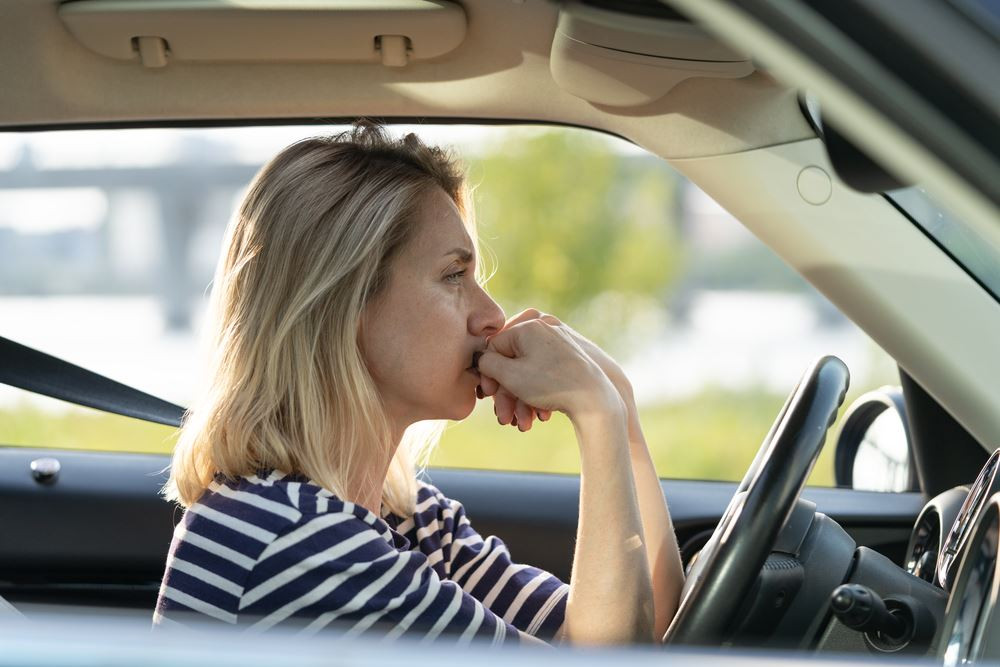 A nervous new driver receiving guidance from an instructor during a driving lesson