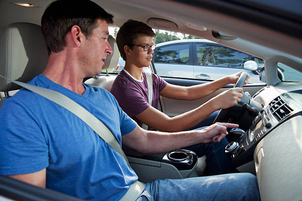 Parent teaching teenager to drive on a residential street.