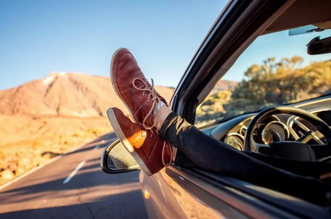 A person changing into sneakers before driving, showcasing the importance of choosing comfortable shoes for safe and effective driving.