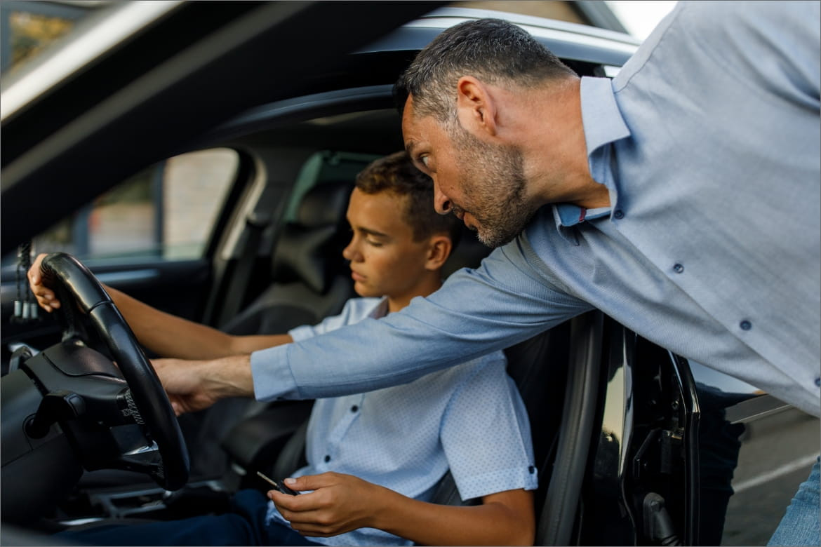 A parent and teen discussing driving tactics with a Get Drivers Ed manual on the table, emphasizing safety and learning.