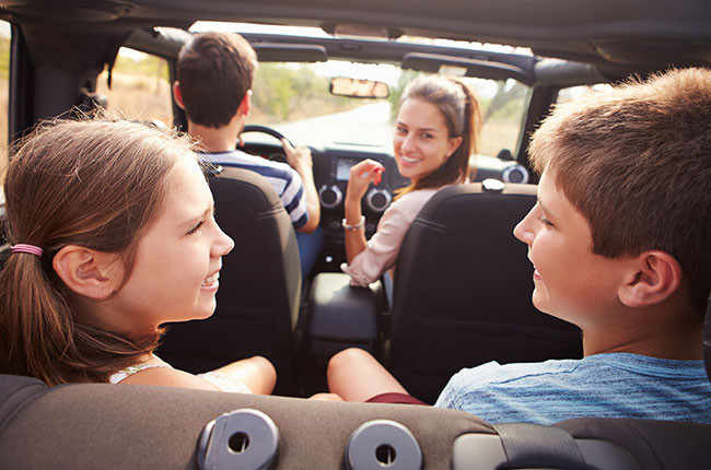 Attentive parent adjusting child's car seat, following safety tips from Get Drivers Ed.