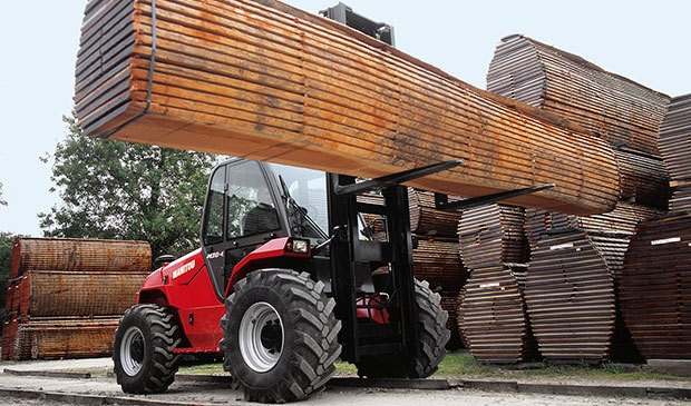 Rough terrain forklift navigating uneven ground on a construction site.