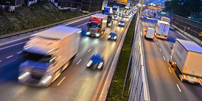 A car safely sharing a lane with a large truck on the highway, demonstrating the importance of understanding blind spots and maintaining safe distances.