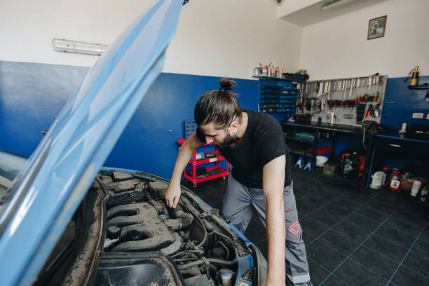 A new driver checking under the hood of a car, learning basic car mechanics to ensure the vehicle is in good condition.