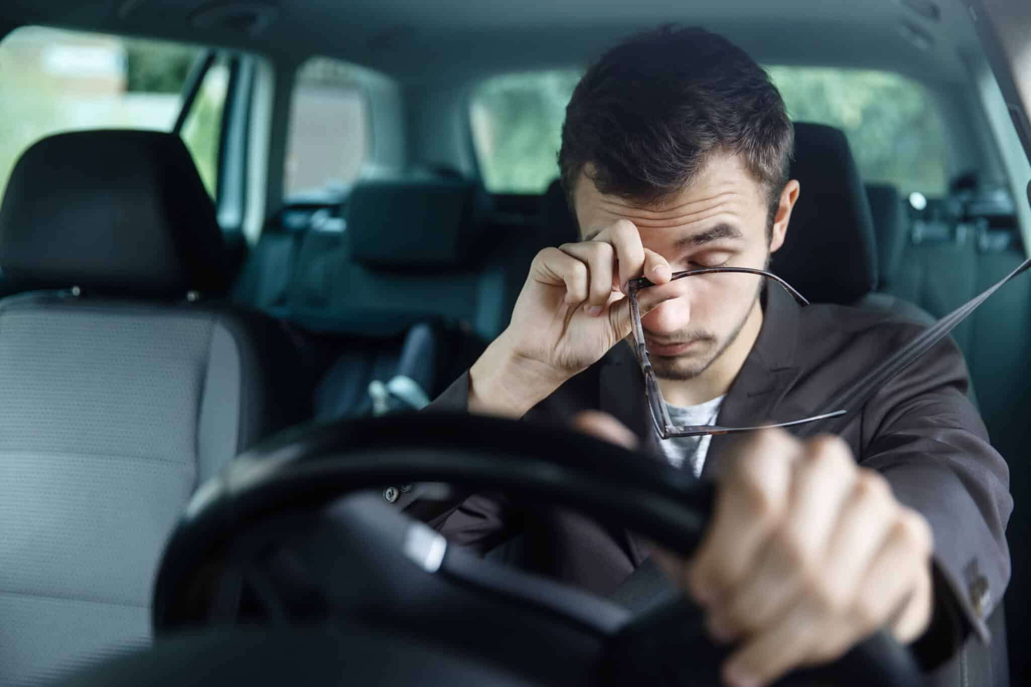 A driver yawning behind the wheel, with a focus on safe driving practices.