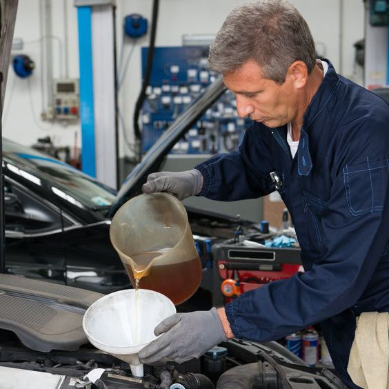 Driver performing a DIY oil change, applying skills learned from Get Drivers Ed.