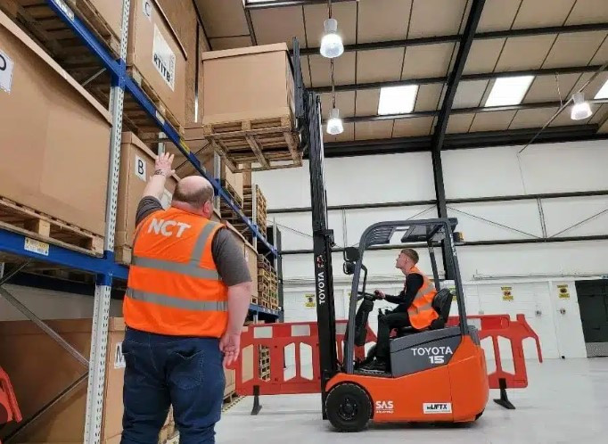 Certified forklift operator carefully maneuvering a forklift in a warehouse, showcasing the importance of forklift certification for safety and productivity