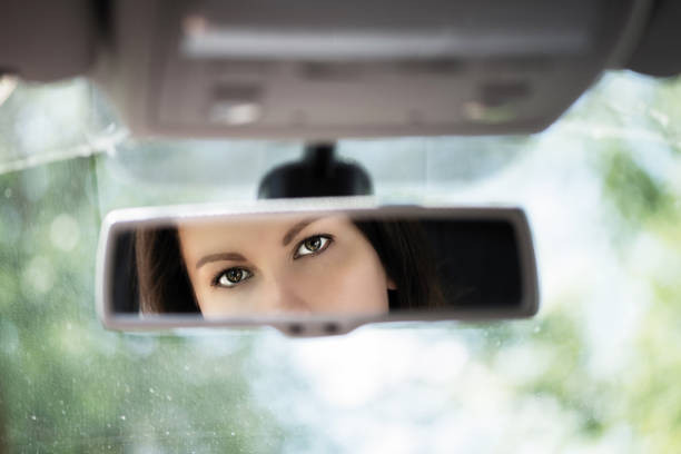 A driver performing a three-point check, looking over their shoulder to ensure safety before changing lanes on the road.