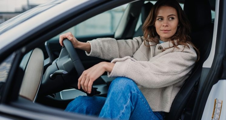 A woman confidently driving her car on a city road, representing the increasing number of female drivers in the U.S. and the changing driving trends.