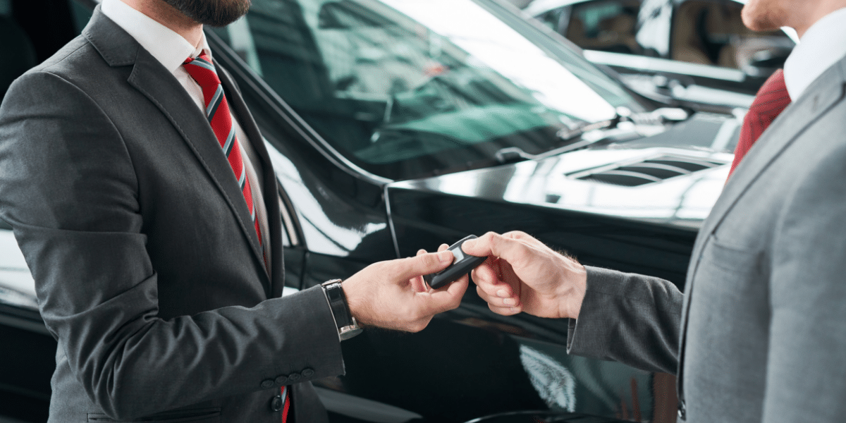 Person signing a car loan agreement with a car key and calculator on the table, symbolizing car financing decisions