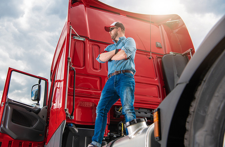 A commercial truck driver in front of a semi-truck after successfully obtaining their CDL through an online CDL course.