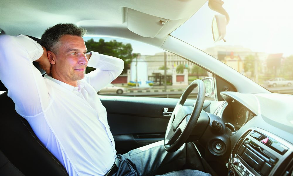 Driver feeling relaxed and happy behind the wheel with a scenic view outside the car window.