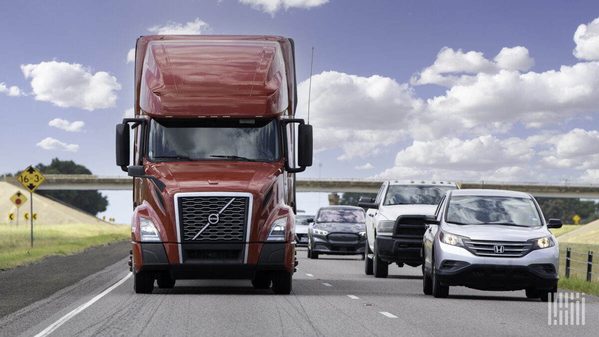 A car driving safely alongside a semi-truck, illustrating the importance of maintaining proper distance and avoiding blind spots as taught by Get Drivers Ed.