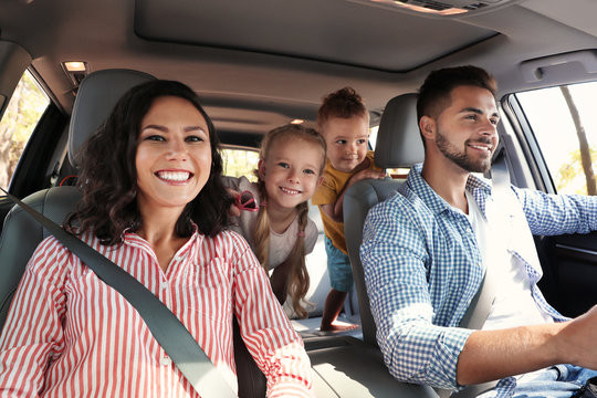 Parent and teenager smiling and discussing driving tactics in a car, experiencing family bonding during a driving lesson.