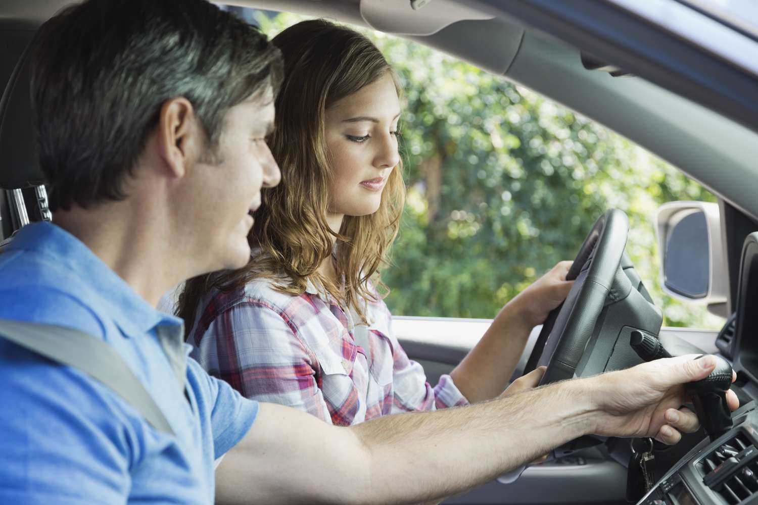 A parent teaching their teen to drive, using Get Drivers Ed's comprehensive materials, in a safe driving environment.