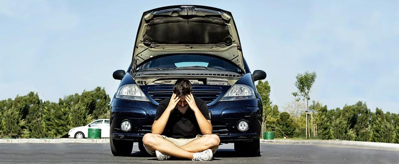 An open car hood with a mechanic checking the engine for common problems like battery issues or overheating.