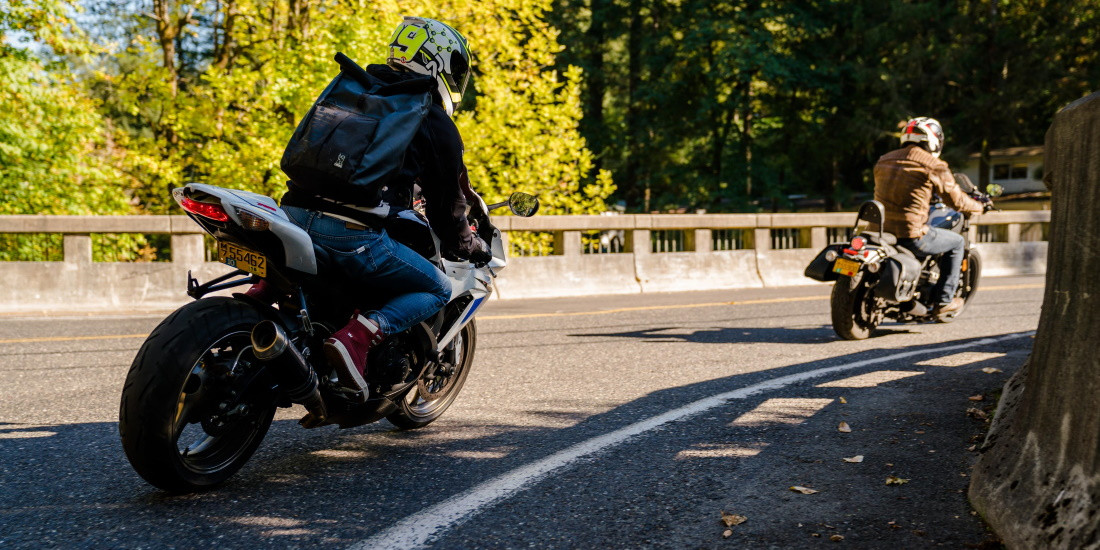 A car and motorcycle safely sharing the road on a sunny day.