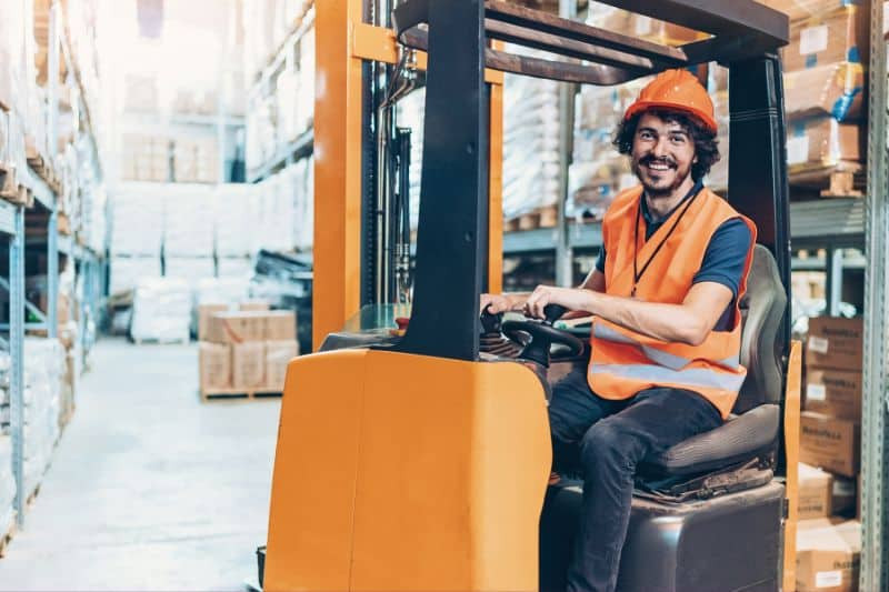 A certified forklift operator handling a pallet in a warehouse, demonstrating compliance with OSHA forklift safety standards.