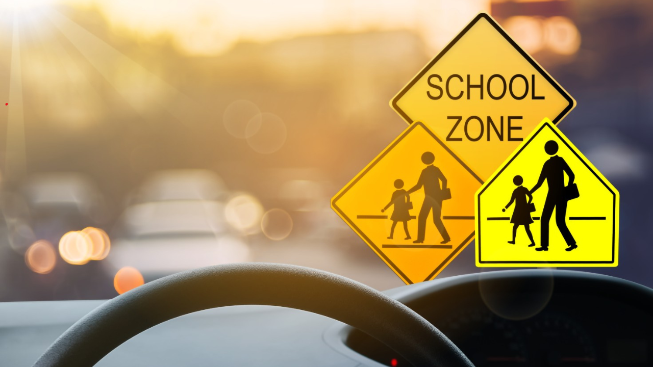 "Car driving carefully in a school zone with children crossing the road"