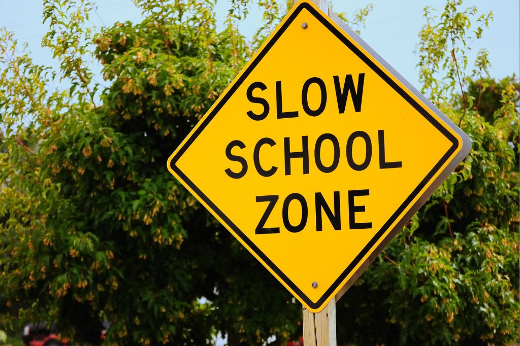 Driver cautiously navigating a school zone with children crossing the street, emphasizing safety tips from Get Drivers Ed