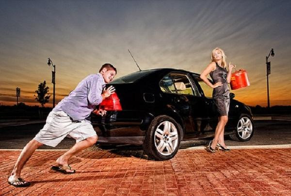 A person standing by their car with an empty fuel gauge, wondering what to do after running out of gas.