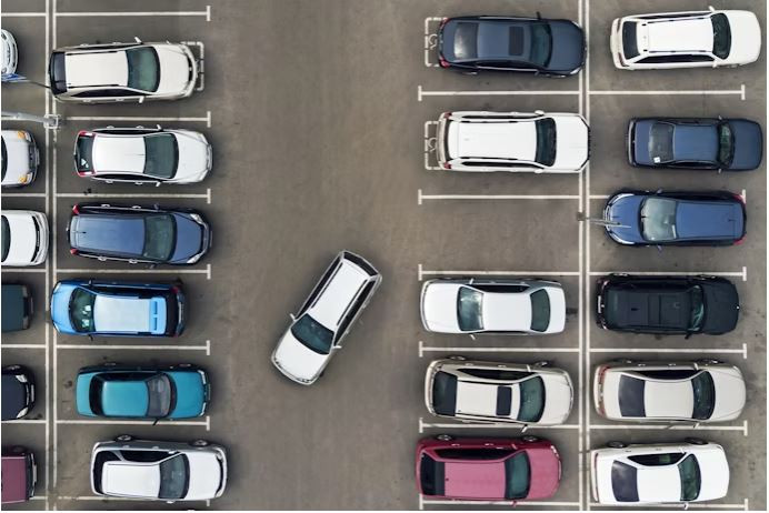 A driver carefully parking their car within the lines in a parking lot, showing proper parking etiquette.