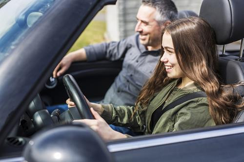 A teenager confidently sitting in the driver’s seat, ready to start driving lessons after showing signs of readiness.