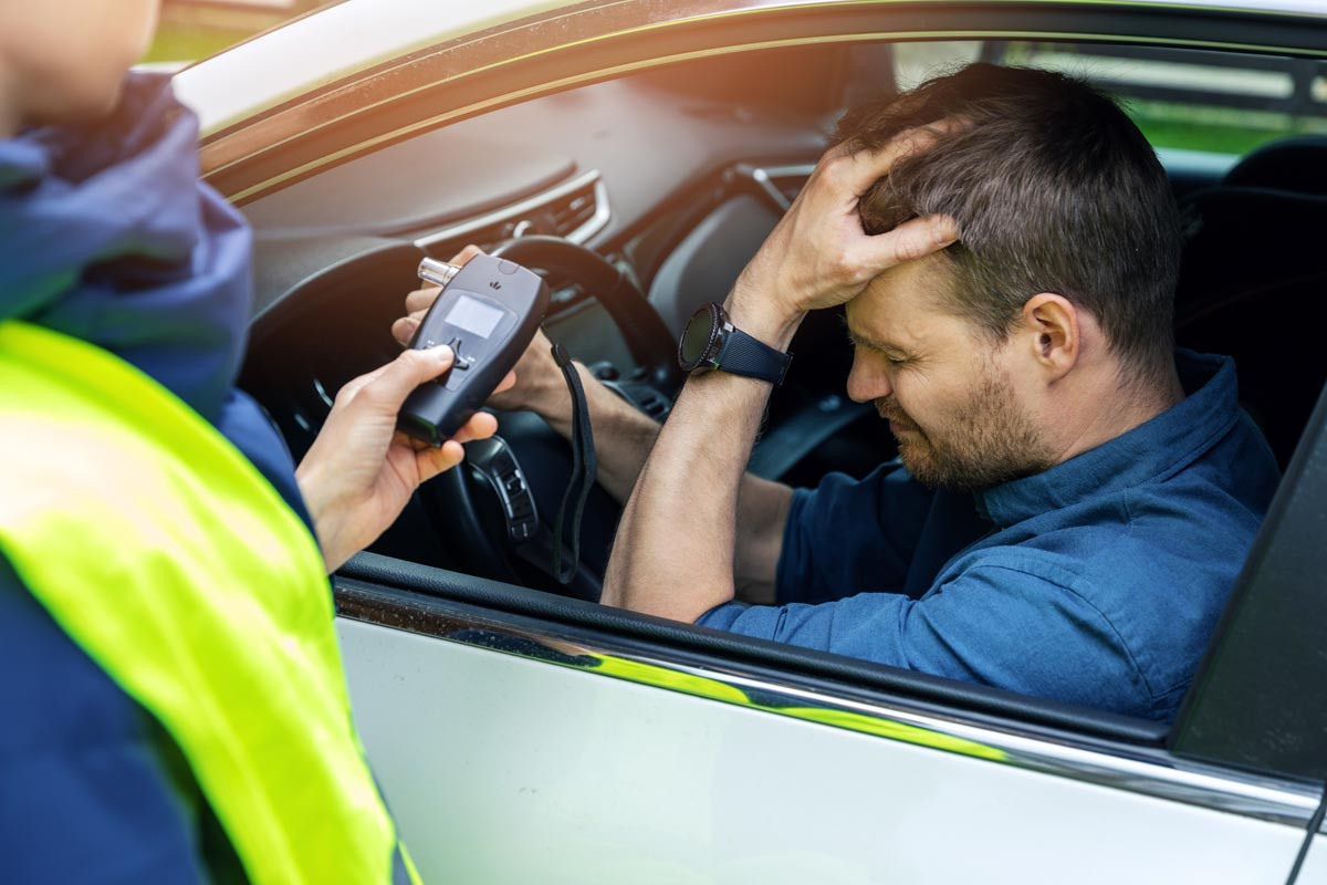 A driver holding car keys with a clear "No Alcohol" symbol, emphasizing the importance of driving sober to avoid consequences.