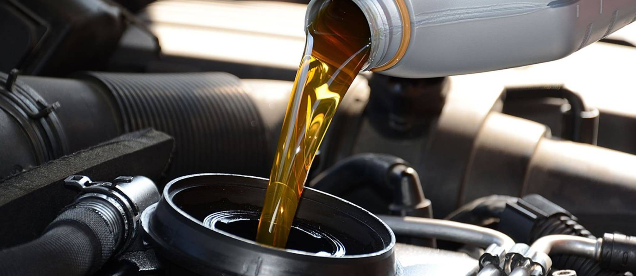 A mechanic pouring fresh oil into a car engine, highlighting the importance of oil changes as part of a comprehensive drivers ed program by Get Drivers Ed.