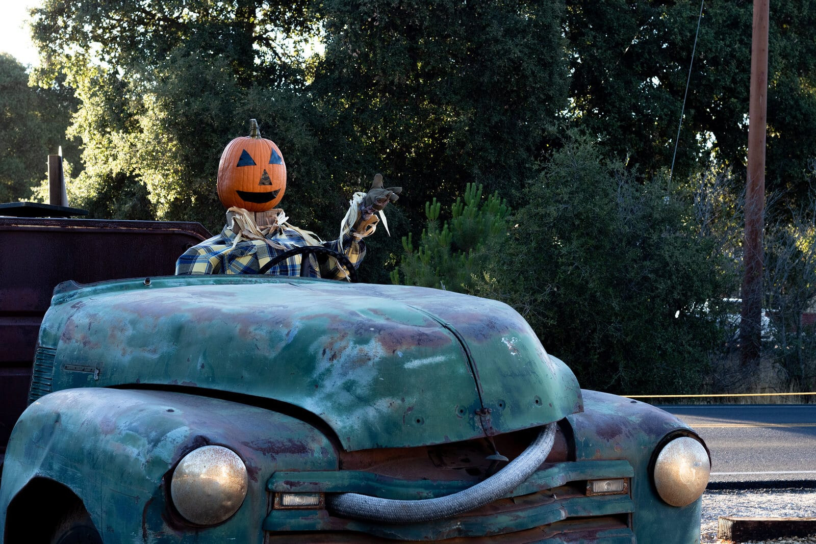 A car driving cautiously down a residential street filled with trick-or-treaters in Halloween costumes at night.